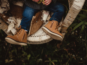 Little boy sitting on a chair wearing leather brown high tops