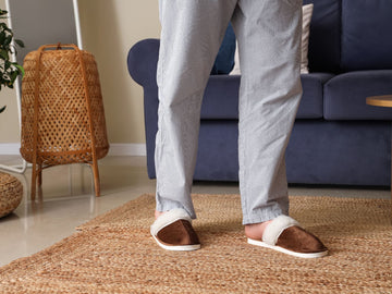 Legs of man wearing brown slippers at home